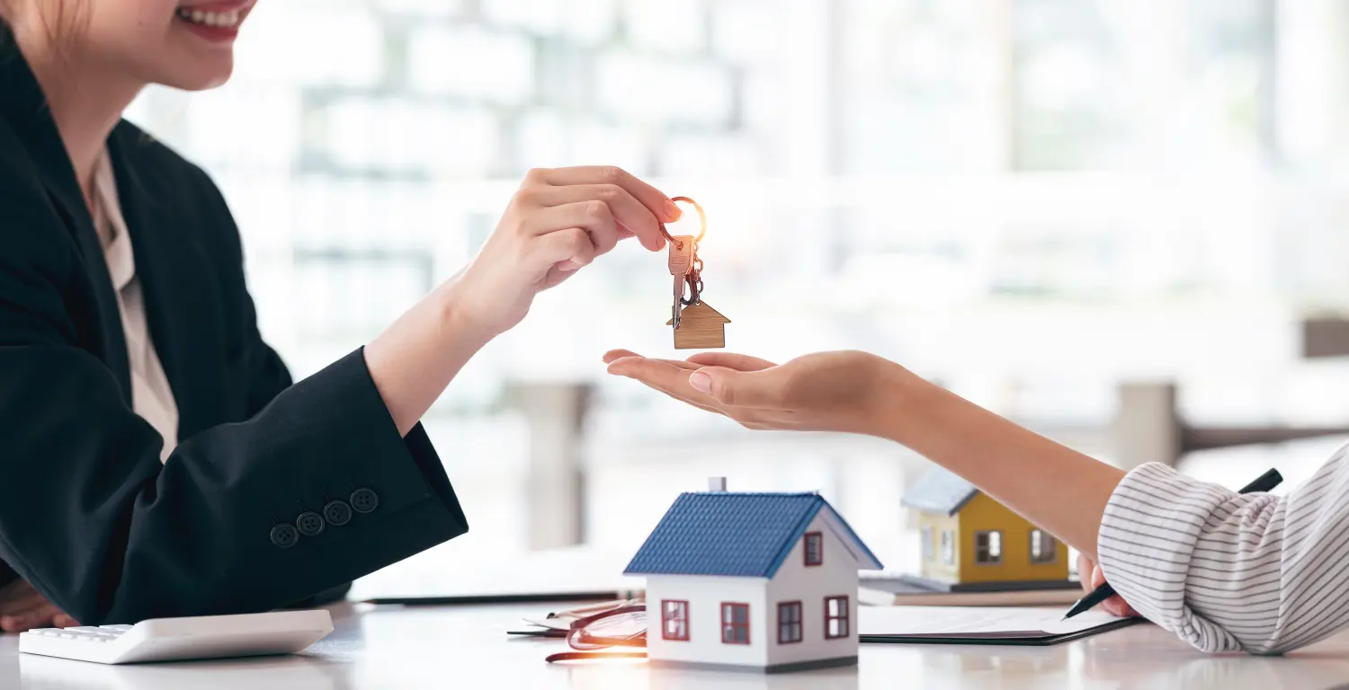 Immobilienmakler oder -vermittler, der sich mit seinem Kunden trifft und ihm nach Abschluss des Geschäfts den Hausschlüssel und das neue Haus übergibt. 